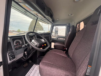 Mack PI64 truck cabin interior showing driver seat, steering wheel, dashboard gauges, and door frame; front windshield and passenger seat visible.