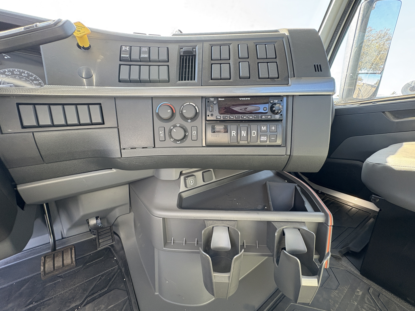 Dashboard view of Volvo VHD64B300 truck cab showing control panel, vents, and cup/coin holders.