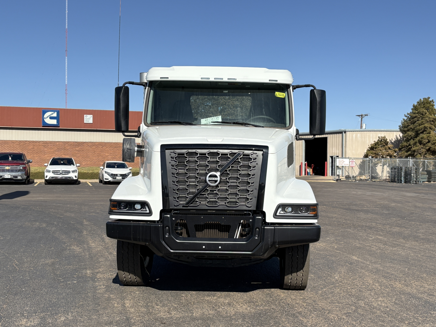 Front view of a Volvo VHD64B300 truck showing large grille with Volvo emblem, headlights, and bumper in a dealership lot.