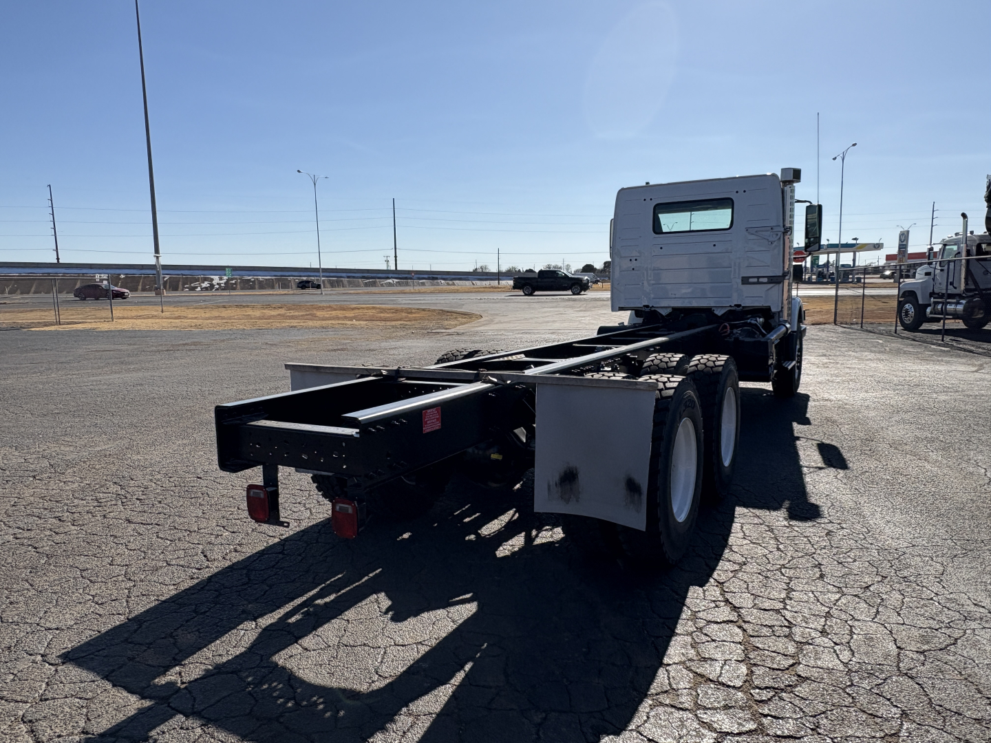 Truck chassis rear and cab of a Volvo VHD64B300 with flatbed frame, dual rear wheels, and back view showing chassis rails.
