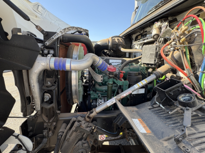 Volvo VHD64B300 engine bay showing turbo hoses, coolant hoses, wiring, and radiator area with engine block and components visible.