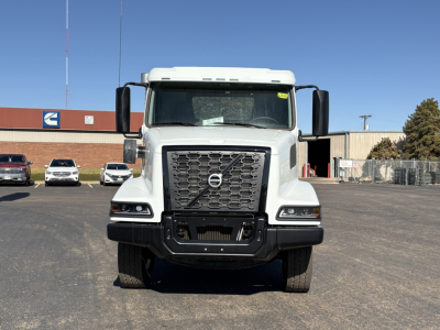 Front view of a Volvo VHD64B300 truck showing large grille with Volvo emblem, headlights, and bumper in a dealership lot.