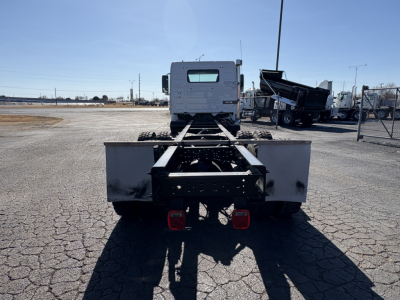Rear view of a Volvo VHD64B300 truck chassis showing dual rear lights and flatbed frame; no cargo, industrial lot setting.