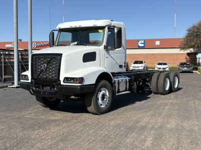 Volvo VHD64B300 tractor truck in white, two-axle cab with dual rear axles, front grille with Volvo emblem, side mirrors, parked outdoors.