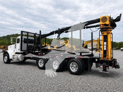 Grapple truck with heavy equipment on flatbed, Peterbilt 367, white cab, orange hydraulic arm at rear, side view, reusable stock photo watermarks visible.