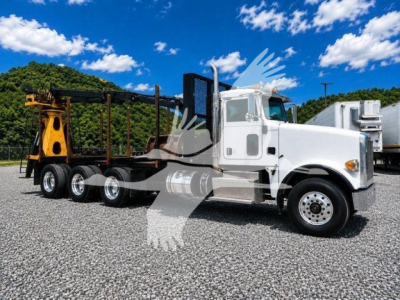Peterbilt 367 truck in service with a grapple trailer, white cab and black chassis, parked on gravel.