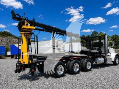 Peterbilt 367 grapple truck in service showing long boom and hydraulic arms with grapple at front, white cab, black chassis, multiple rear axles, gravel lot.