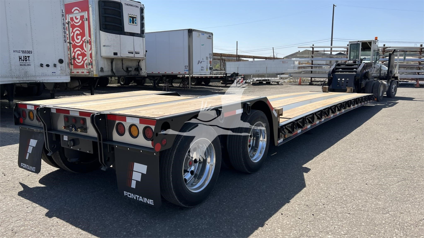 Fontaine lowboy trailer in a yard showing steel deck and triple-axle rear with FONTAINE branding on mud flaps
