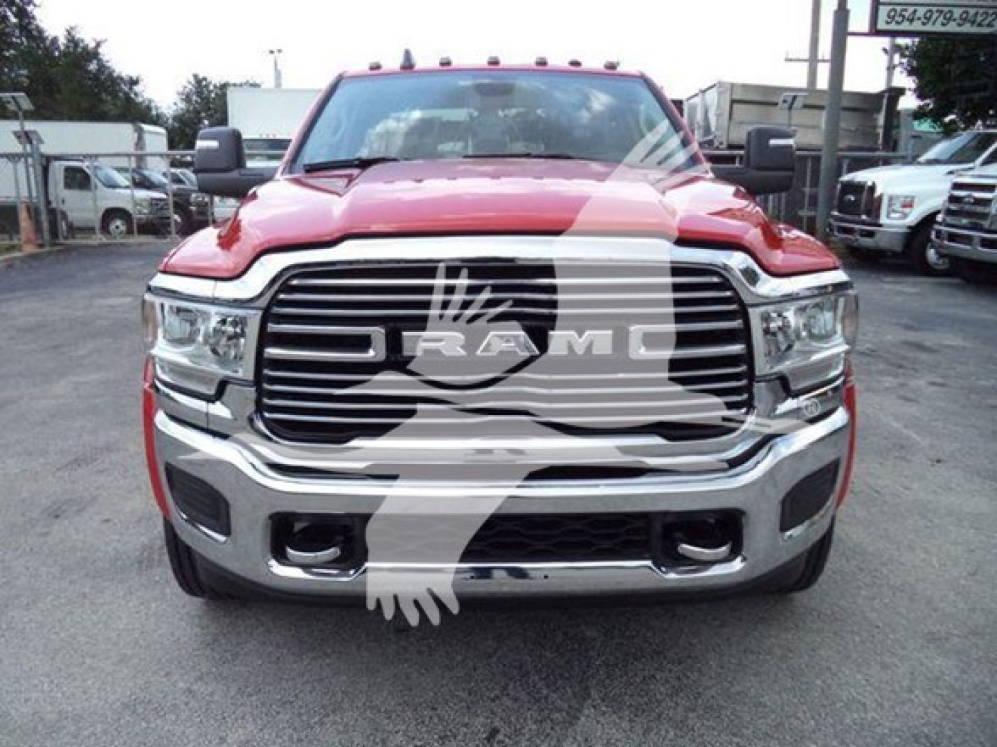 Front view of red 2024 Ram pickup with large chrome grille and RAM emblem; truck appears in a dealership lot.