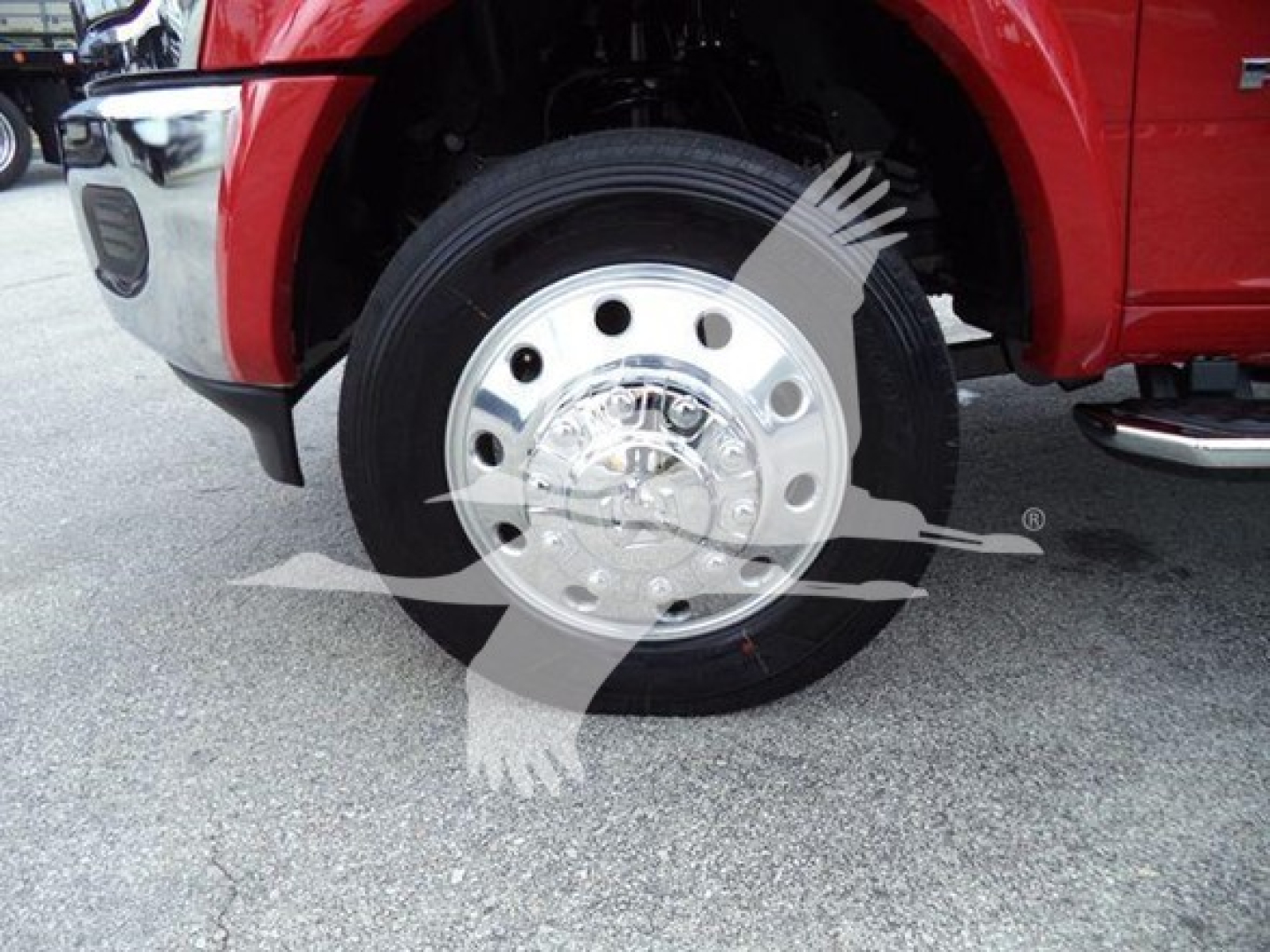 Truck wheel and front fender of a red 2024 Ram Laramie with polished steel wheel and tire.
