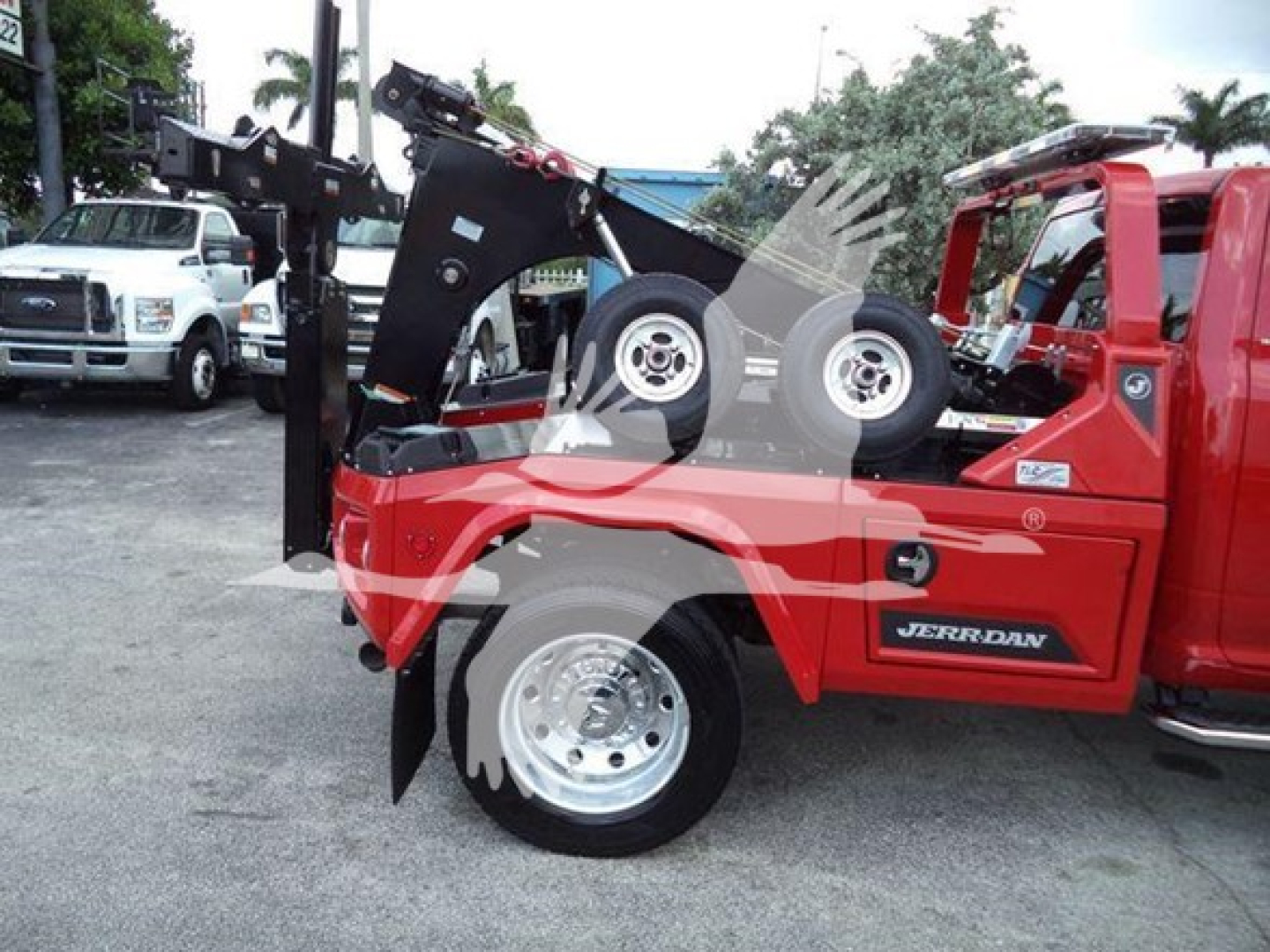Ram 2024 Ram Laramie pickup with tow winch system mounted on red bed, front wheel visible, dealership lot in background.