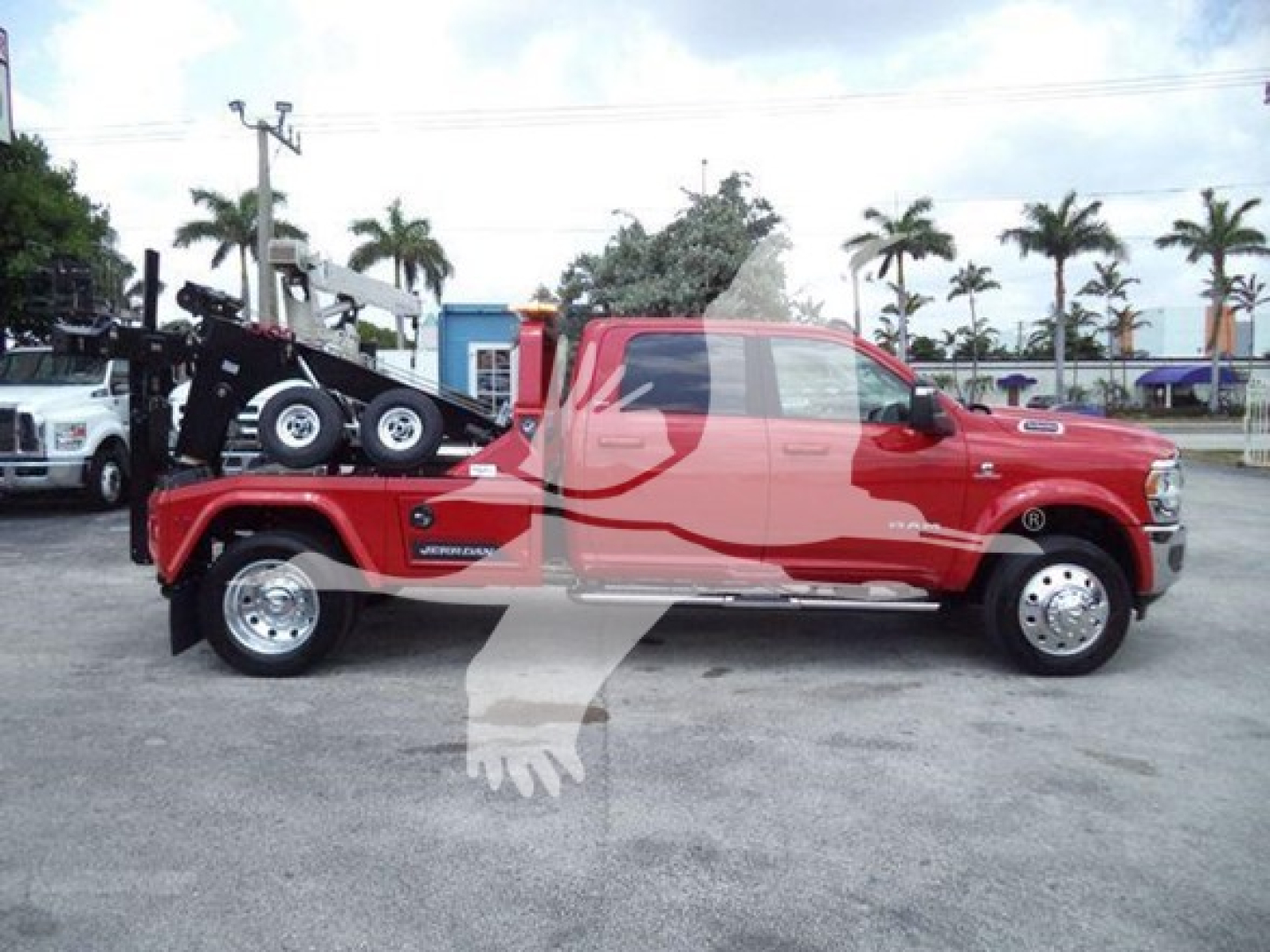 Ram pickup truck in red with heavy tow winch equipment mounted behind cab, showing side profile and wheels.