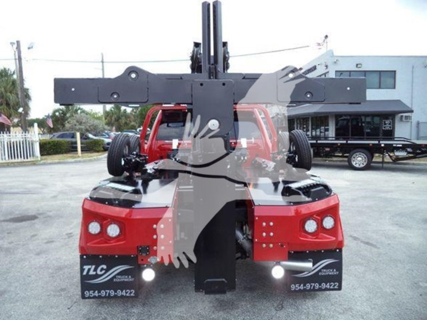 Truck with a large front winch assembly showing TLC trailer service contact numbers and dealership area codes on the lower front panels.