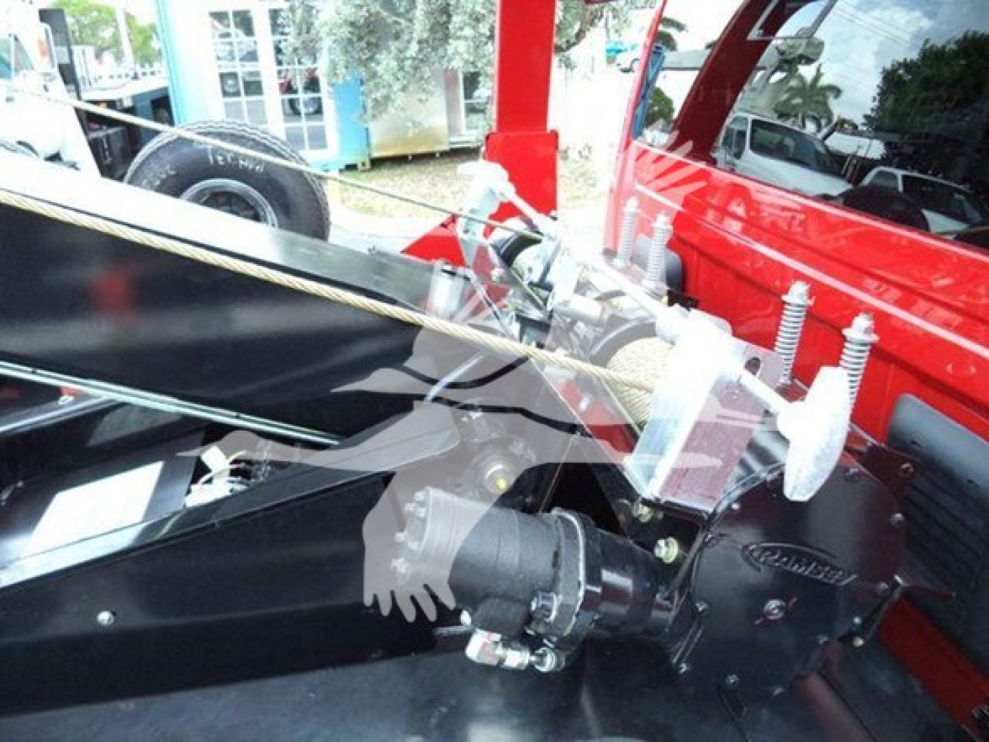 Winch-equipped Ram pickup engine bay view showing hydraulic winch drum and mounting hardware, front area with cable and hooks.