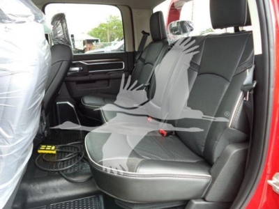 Ram 2024 Laramie cabin interior showing rear bench seat in black fabric with light stitching, door panel, seat belts, and protective plastic on front seat visible.