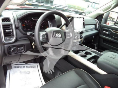 Ram pickup truck interior showing steering wheel, large center touchscreen, instrument cluster, and front seats from driver's side.