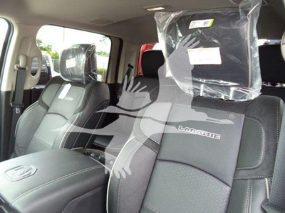 Ram 1500 Laramie interior showing front seats with plastic-wrapped headrest and Laramie badge on seat, cabin view