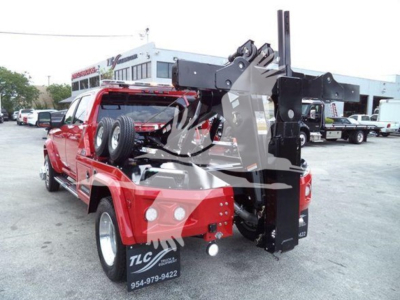 Truck bed with a mounted winch system and hydraulic arm on a red Ram pickup showing a hydraulic winch crane assembly.
