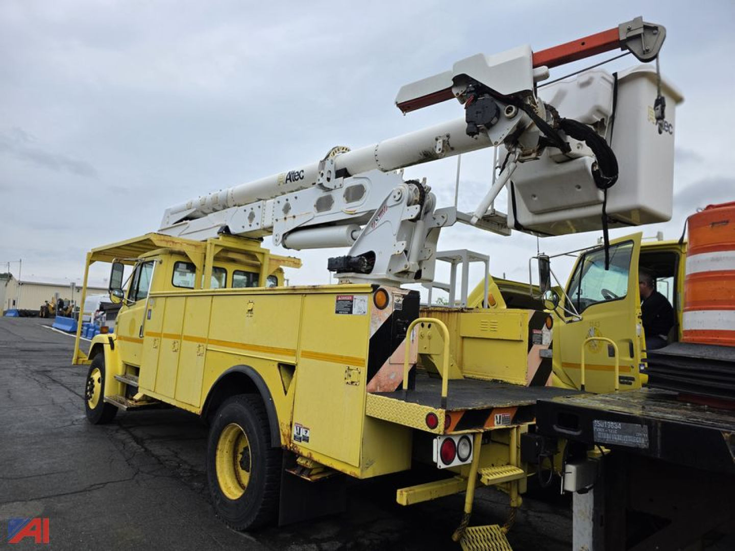 Freightliner FL70 bucket truck with Altec boom and yellow utility body, mounted on a flatbed trailer, side and rear views showing bucket lift and stabilizers.