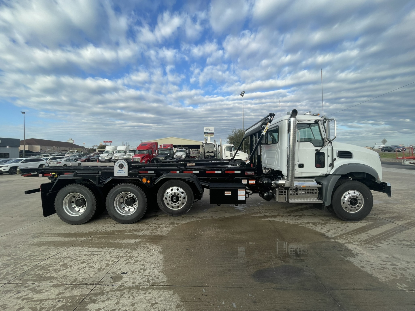 2026 Mack GR64B roll-off truck side view showing cab, hydraulic hooklift, and multiple rear axles.