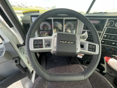 Dashboard and steering wheel of a Mack GR64B truck cab showing the Mack logo on the center of the steering wheel, gauge cluster, and control panels.