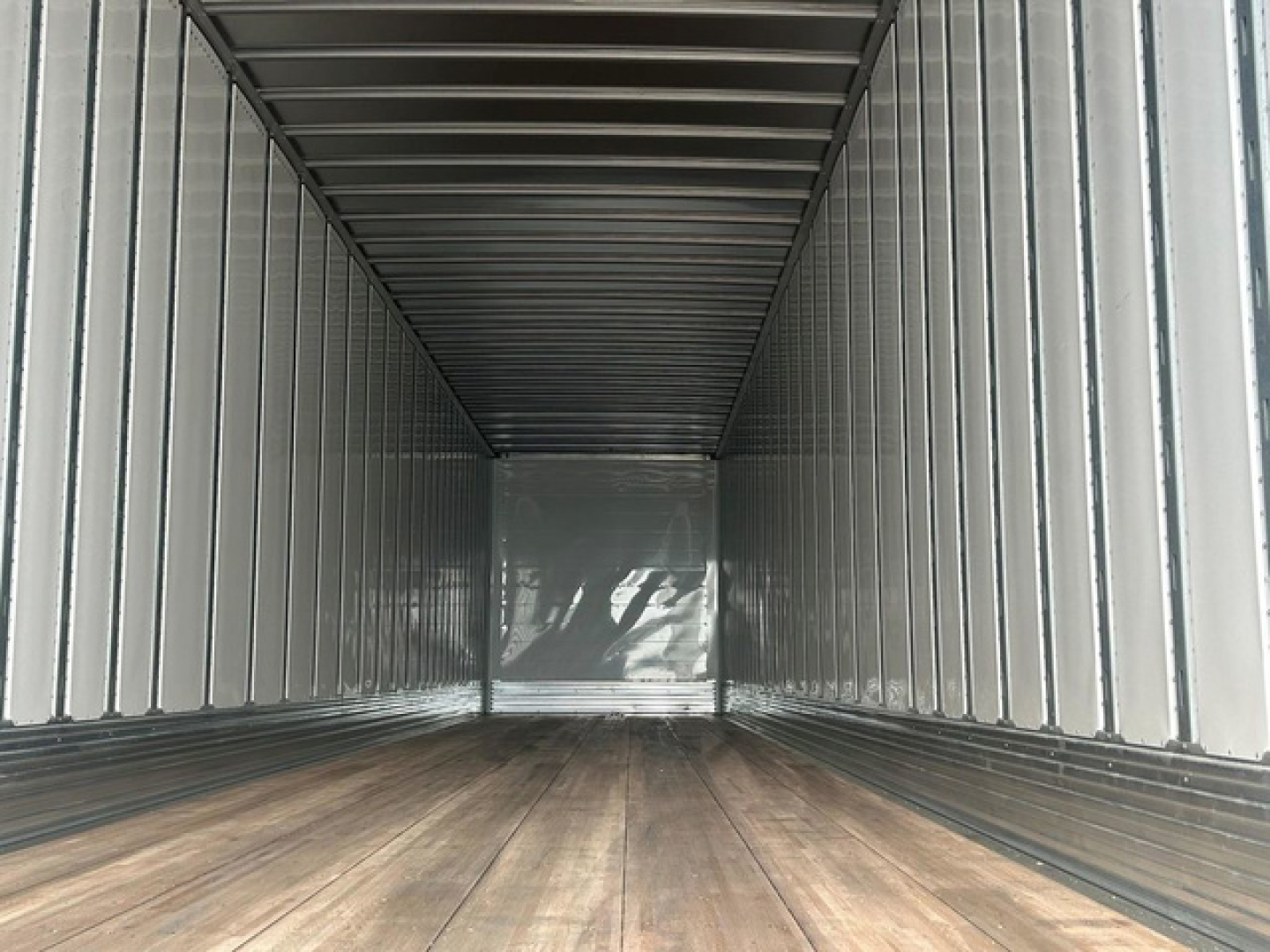 Trailer interior empty cargo space with wooden floor and metal panels, long rectangular van-like trailer.