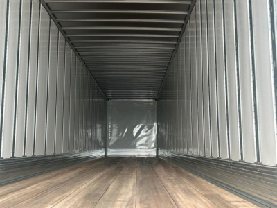Trailer interior empty cargo space with wooden floor and metal panels, long rectangular van-like trailer.
