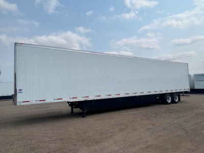Trailer with long rectangular box and tandem axles, aluminum exterior, no visible branding. Side shows reflective tape along lower edge; undercarriage and landing gear visible.