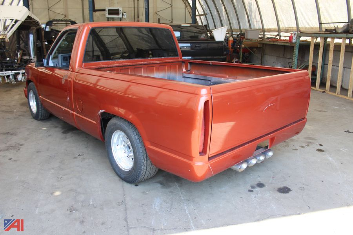 Chevrolet C/K 1500 pickup truck rear/right 1992 model in orange, bed visible, 2WD, single cab with rear bumper and dual exhaust visible.