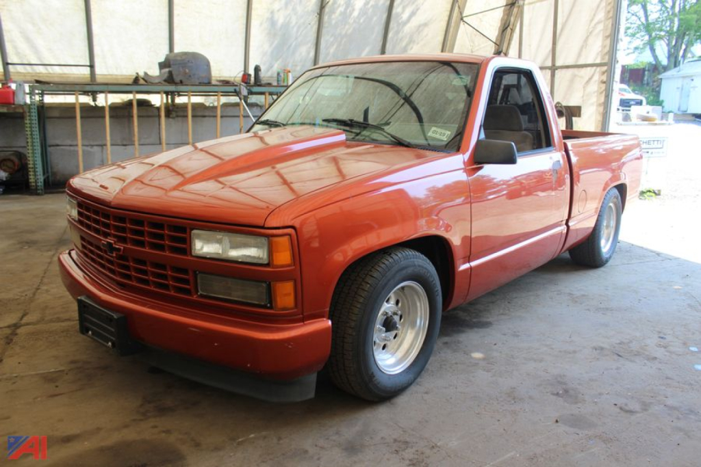 Front three-quarter view of a red 1992 Chevrolet C/K 1500 pickup truck in a covered area.