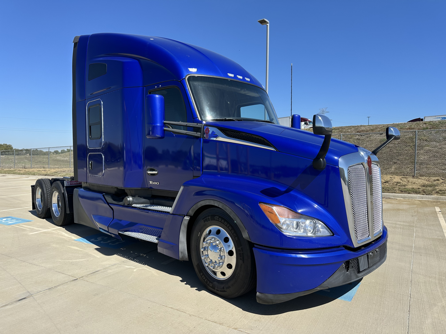 Kenworth T680 conventional sleeper truck in blue, front three-quarter view showing chrome grille, dual side mirrors, and sleeper cab.