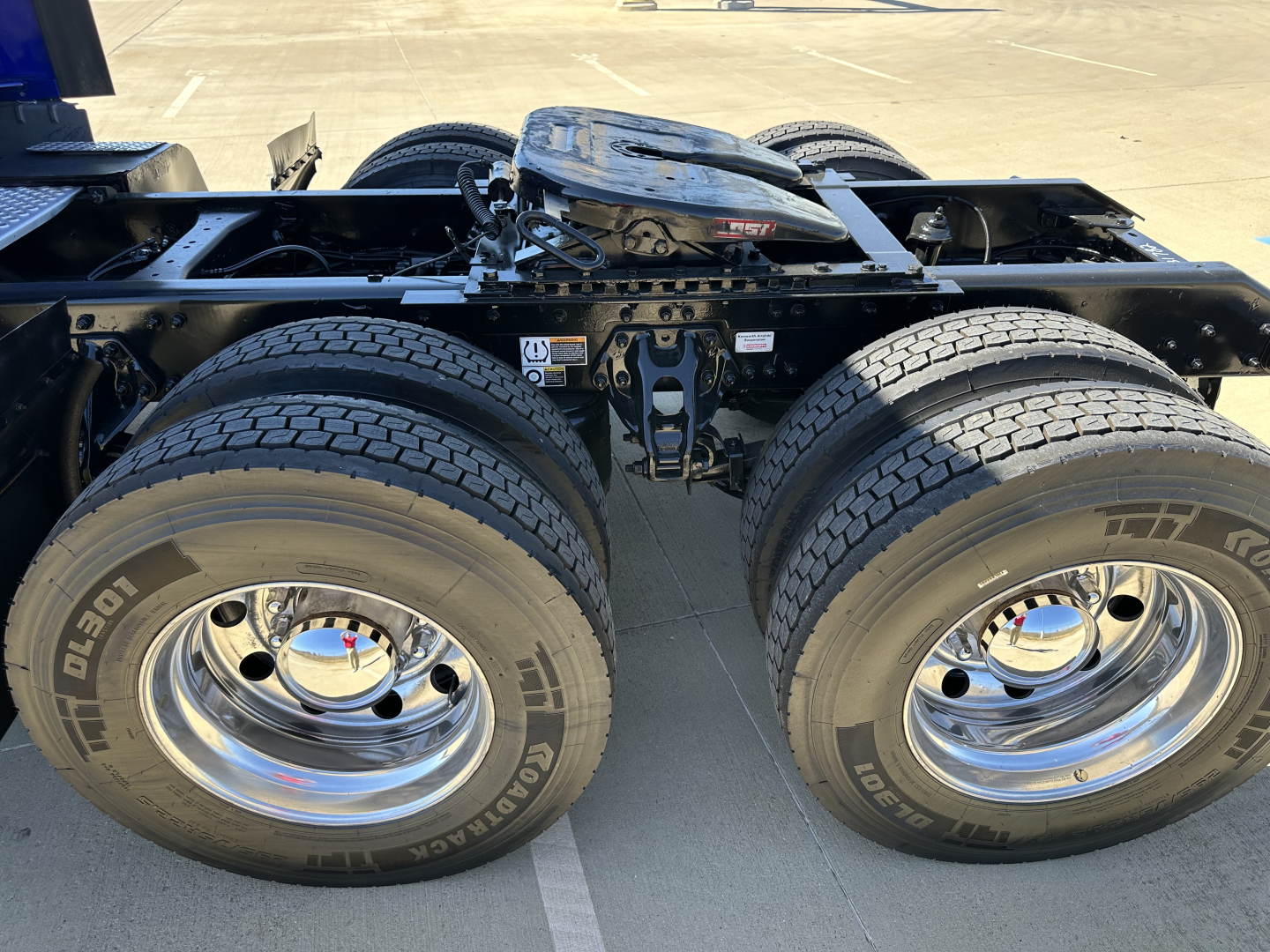 Kenworth T680 chassis with dual rear axles and interaxle connections, view of the back undercarriage showing tires and chrome wheels.