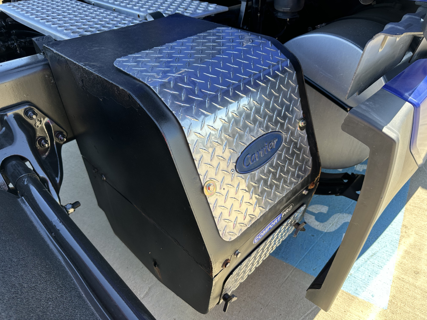 Kenworth T680 engine bay side showing diamond plate steps and coolant/air filter housing with Kenworth emblem.