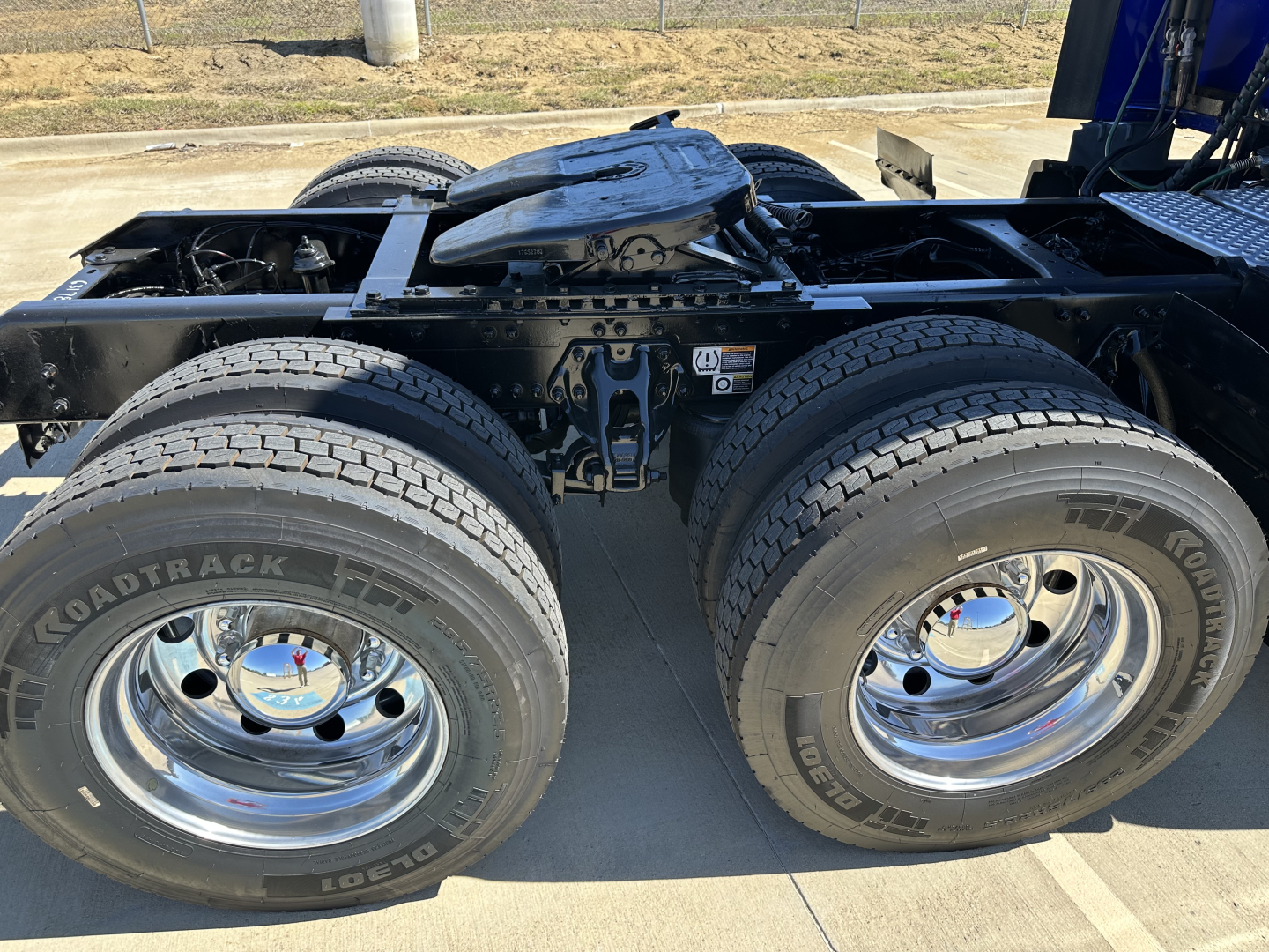 Kenworth T680 chassis with dual rear axles and tires, fuel/air lines visible, fifth wheel not visible, chrome wheels on both rear axles, VIN and stock details not shown in image.