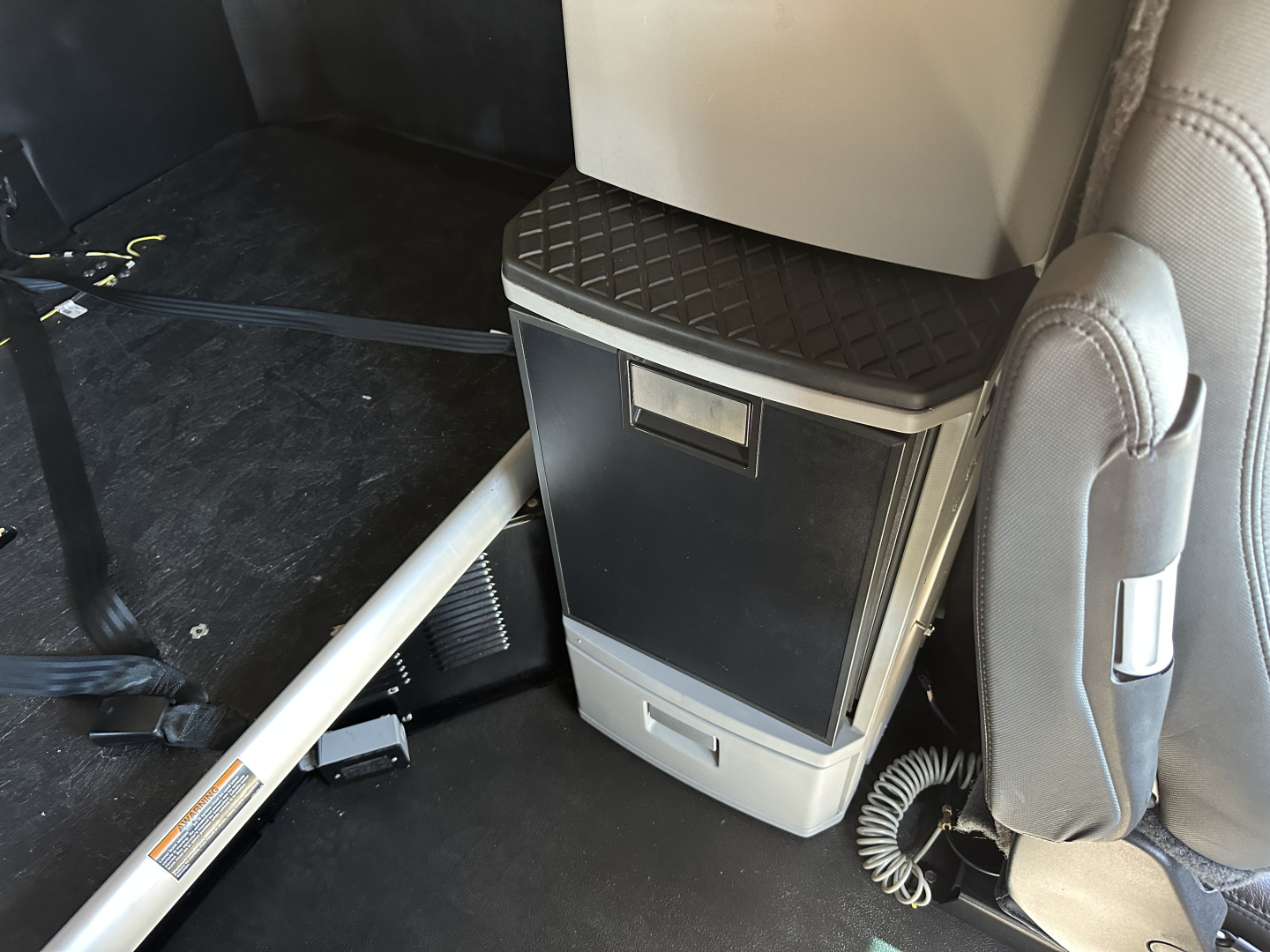 Kenworth T680 interior view showing overhead cabinet and center console with a small storage drawer and cubby; portion of seat and floor visible.
