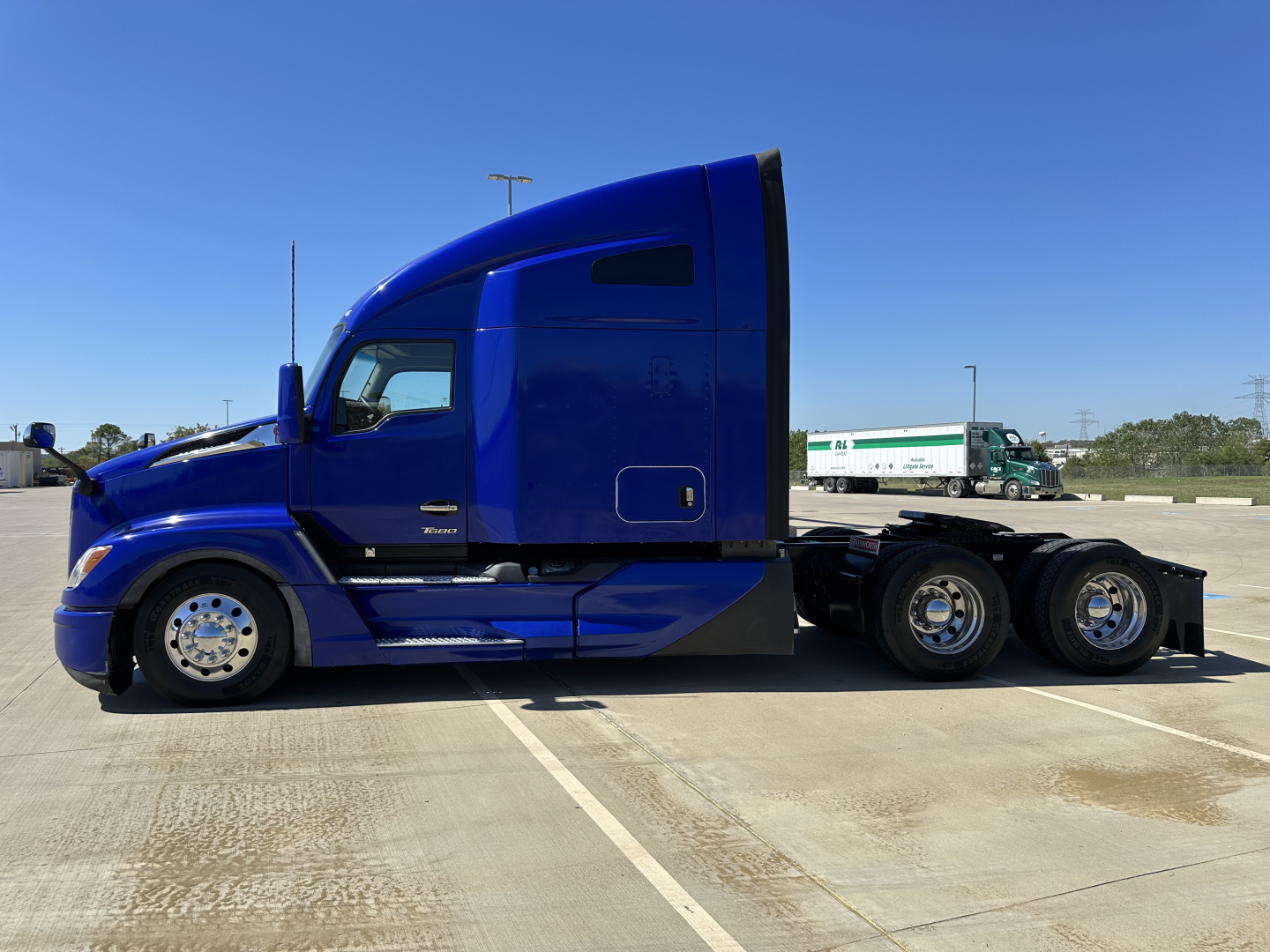 Kenworth T680 sleeper tractor in blue side profile showing cab and rear wheels with tag identifiers not legible.