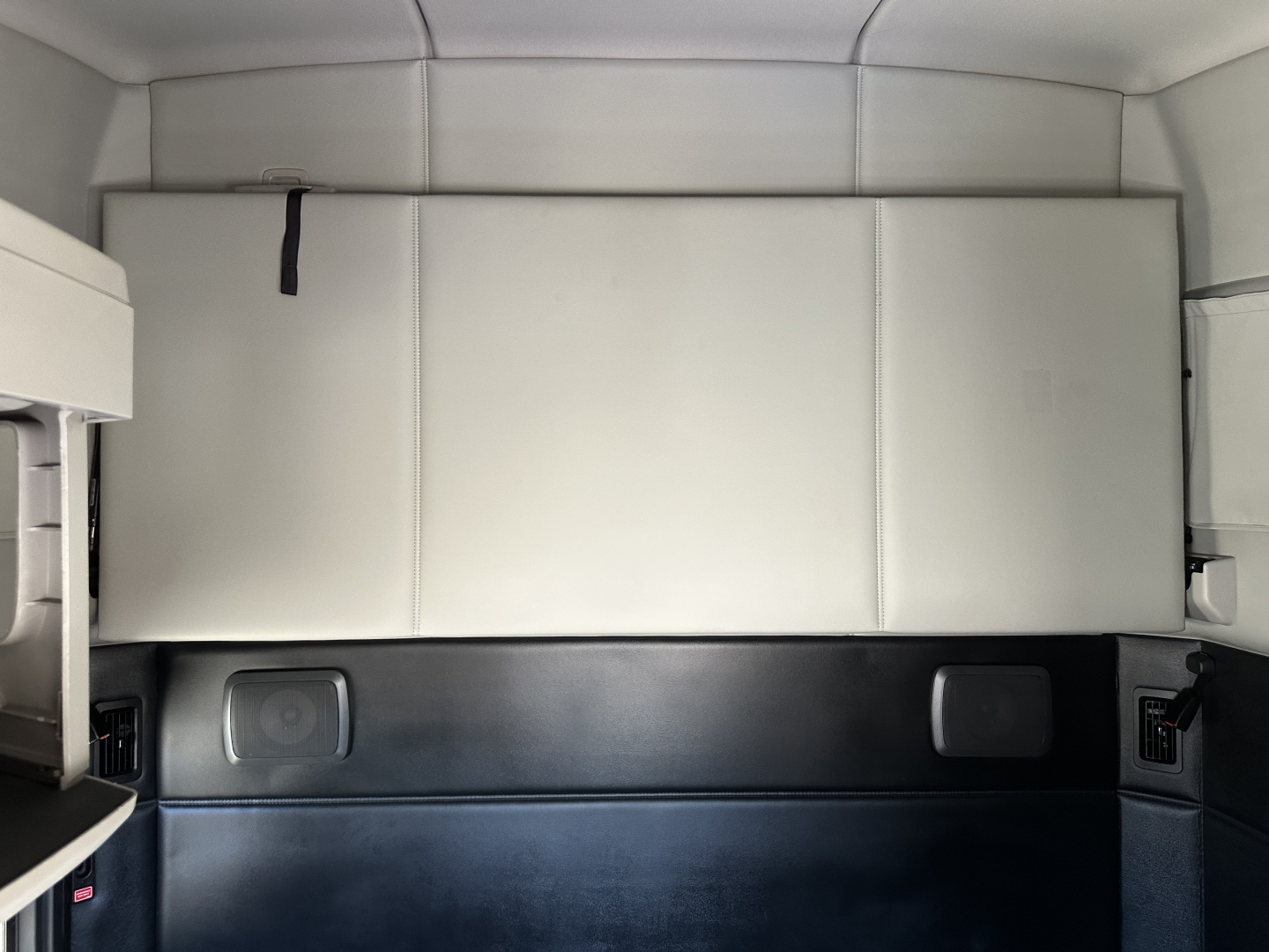 Kenworth T680 sleeper cab interior cargo area with white partition box and black lower panels.