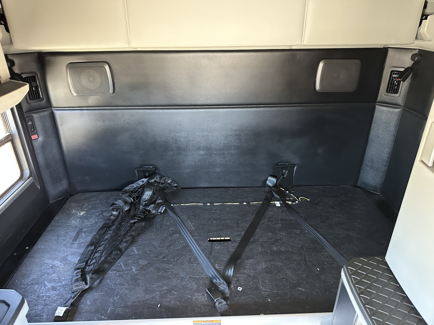 Kenworth T680 cargo area with storage near sleeper, rear interior showing cargo straps and flat floor.