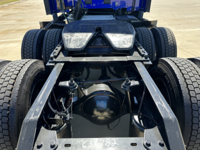 Kenworth T680 chassis rear view showing fifth wheel, dual rear axles, and drivetrain components with visible grounding and suspension parts.