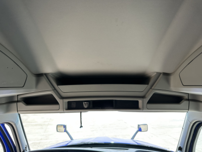 Kenworth T680 interior cab view with sun visor and overhead console; windshield shows side mirrors and bright outside.