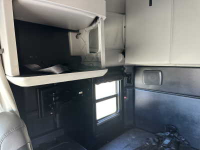 Kenworth T680 interior view showing sleeper cab area with overhead storage and window; equipment label not visible.