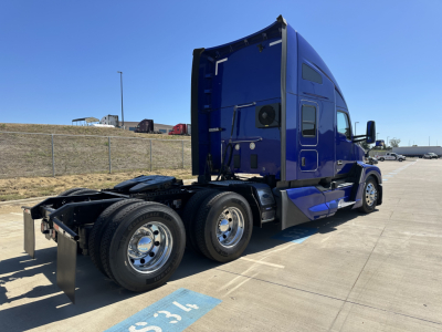 Kenworth T680 convention sleeper truck in blue, rear side view showing twin rear axles and fuel tanks.