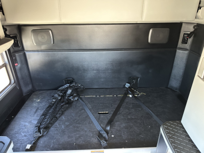 Kenworth T680 cargo area with storage near sleeper, rear interior showing cargo straps and flat floor.