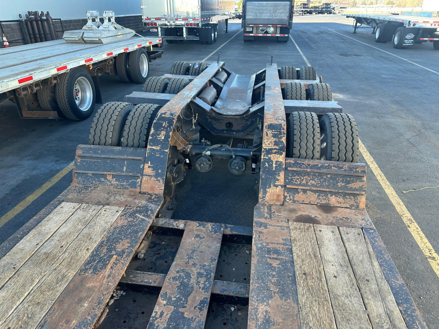 Farm-style view of a Fontaine 55 LCC lowboy trailer frame showing multiple axles and deck sections with worn paint and metal components.