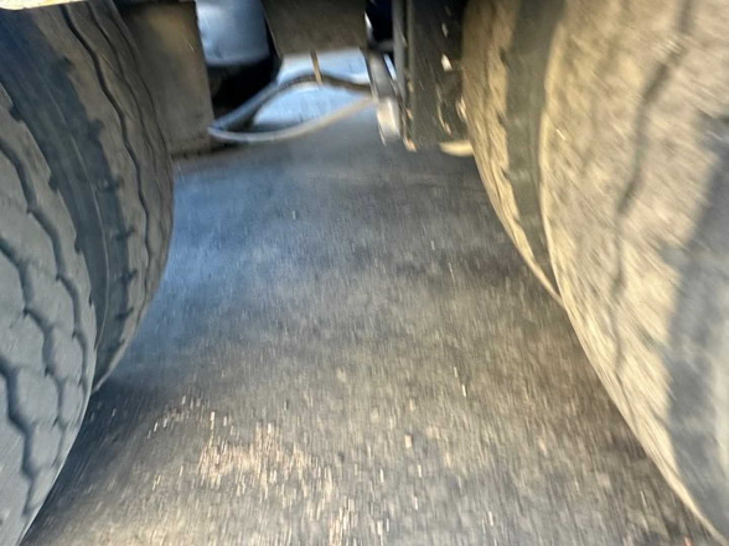 Rear view between dual truck tires on a Fontaine 55 LCC lowboy trailer showing worn deck surface and wheel wells.