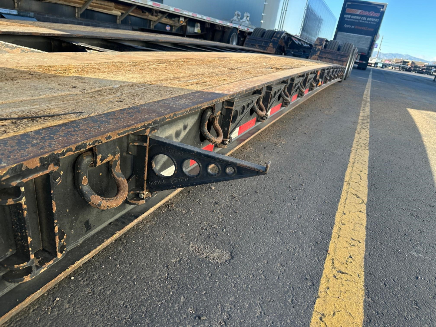 Trailer deck edge of Fontaine lowboy trailer showing attachment hooks and edge hardware