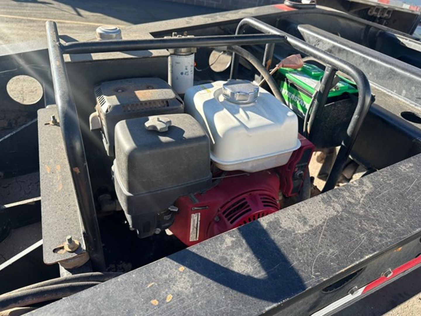 Trailer engine bay showing gas-powered generator with white plastic fuel tank, red engine, and surrounding frame rail on Fontaine 55 Lcc lowboy.
