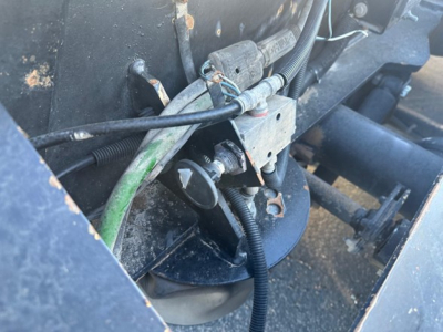 Trailer hitch area of a Fontaine 55 Lcc lowboy showing hydraulic line, cables, green hose, and metal mounting bracket