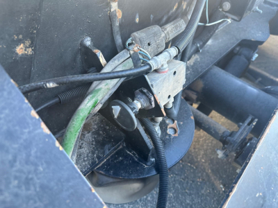  Fontaine lowboy trailer wheel hub area showing hydraulic line and wiring harness with green hose and metal bracket.