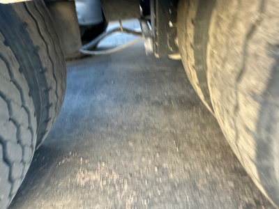 Left and right tandem trailer tires on a Fontaine lowboy showing wheel wells and a dirt surface between tires.